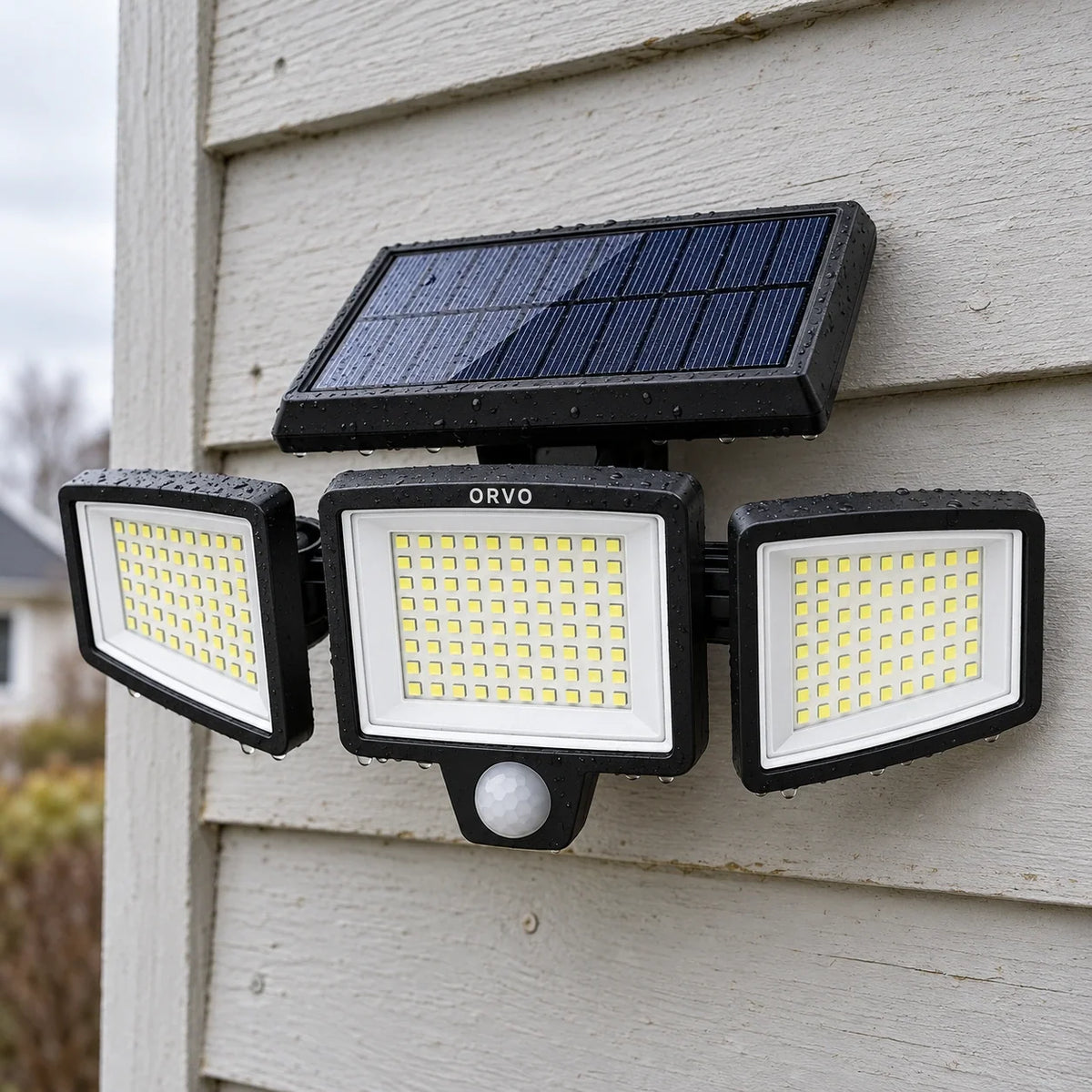 Orvo solar buitenlamp met drie brandende lampkoppen boven een garagedeur in de schemering, een man loopt met zijn fiets naar binnen